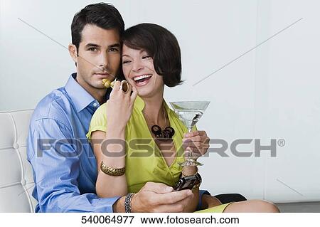 Young woman feeding olive to a mid adult man sitting with her on a chair View Large Photo Image Stock Photo - Young woman feeding olive to a mid adult man sitting with her on a chair. Fotosearch