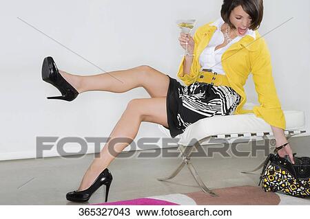 Young woman holding a glass of martini and reaching out a hand bag View Large Photo Image Stock Image - Young woman holding a glass of martini and reaching out a hand bag. Fotosearch