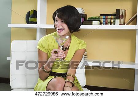 Young woman holding a martini glass and smiling View Large Photo Image Stock Photograph - Young woman holding a martini glass and smiling. Fotosearch