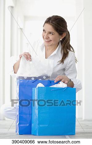 Young woman holding shopping bags and smiling View Large Photo Image Stock Photograph - Young woman holding shopping bags and smiling. Fotosearch