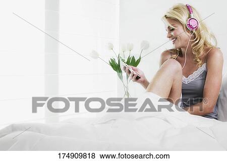 Stock Photo - Young woman listening to an MP3 player and smiling. Fotosearch