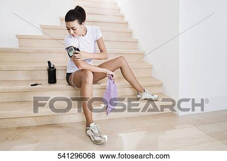 Young woman looking at a pedometer on her arm and listening to music View Large Photo Image Stock Photo - Young woman looking at a pedometer on her arm and listening to music. Fotosearch