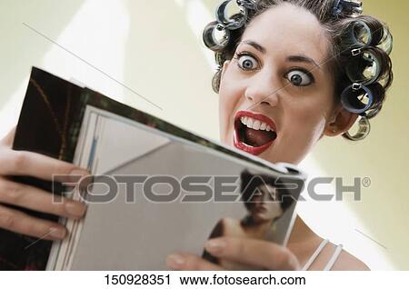 Young woman reading a magazine View Large Photo Image Stock Image - Young woman reading a magazine. Fotosearch
