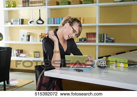 Young woman sitting at a table and reading a book View Large Photo Image Stock Image - Young woman sitting at a table and reading a book. Fotosearch