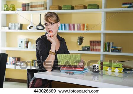 Young woman sitting at a table and thinking View Large Photo Image Stock Photo - Young woman sitting at a table and thinking. Fotosearch