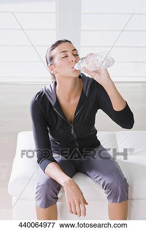 Young woman sitting on the bed and drinking water View Large Photo Image Stock Photo - Young woman sitting on the bed and drinking water. Fotosearch
