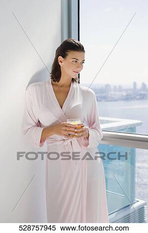 Young woman standing and holding a glass of juice View Large Photo Image Stock Photography - Young woman standing and holding a glass of juice. Fotosearch