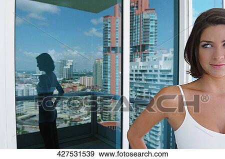 Young woman standing in a balcony View Large Photo Image Stock Photo - Young woman standing in a balcony. Fotosearch