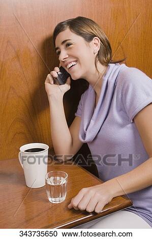 Young woman talking on a mobile phone in a cafe View Large Photo Image Stock Image - Young woman talking on a mobile phone in a cafe. Fotosearch