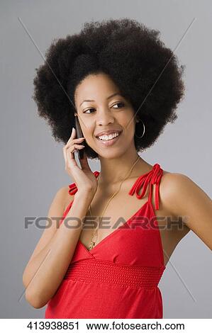 Stock Image - Young woman talking on a mobile phone and smiling. Fotosearch