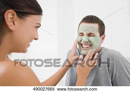Young woman touching the facial mask of a young man and smiling View Large Photo Image Stock Photography - Young woman touching the facial mask of a young man and smiling. Fotosearch