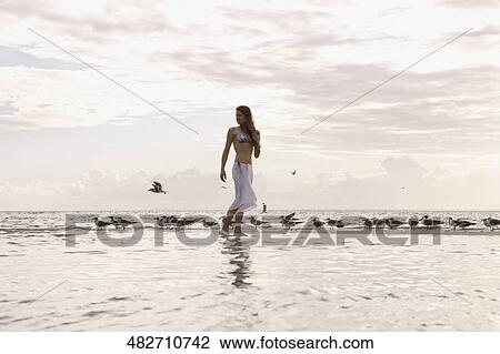 Young woman walking on the beach View Large Photo Image Stock Image - Young woman walking on the beach. Fotosearch