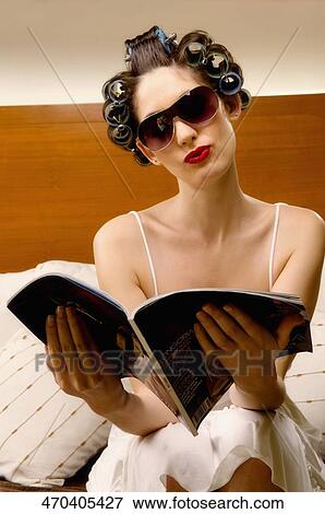 Stock Photo - Young woman wearing hair rollers and reading a book. Fotosearch