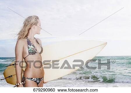 Young woman with a surfboard standing on the beach View Large Photo Image Stock Image - Young woman with a surfboard standing on the beach. Fotosearch