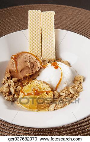 Stock Image - Assorted ice creams scoops garnished with nuts and wafers. Fotosearch