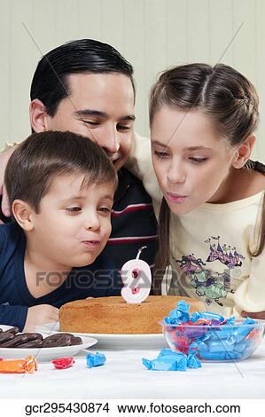 Boy and a girl blowing out birthday candles with their father View Large Photo Image Picture - Boy and a girl blowing out birthday candles with their father. Fotosearch