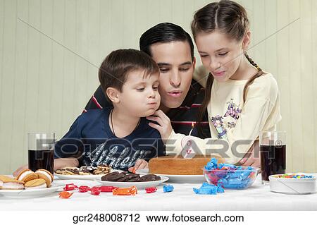 Boy and a girl blowing out birthday candles with their father View Large Photo Image Stock Image - Boy and a girl blowing out birthday candles with their father. Fotosearch