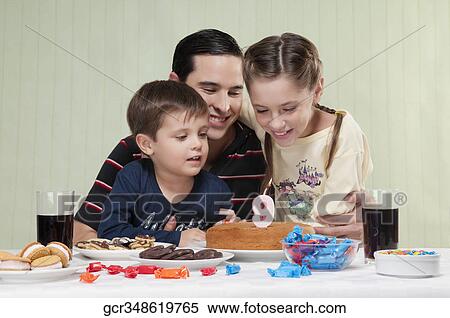 Boy and a girl blowing out birthday candles with their father View Large Photo Image Stock Photography - Boy and a girl blowing out birthday candles with their father. Fotosearch