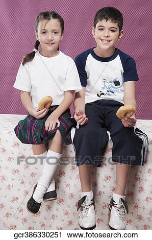 Boy and his sister holding donuts and smiling View Large Photo Image Stock Image - Boy and his sister holding donuts and smiling. Fotosearch