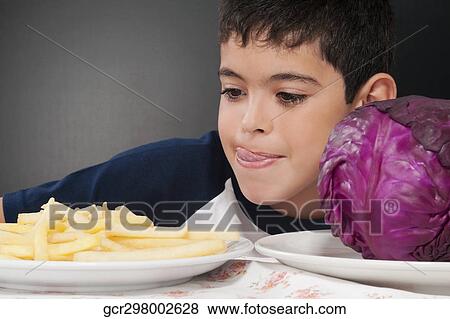 Boy choosing between a plate of French fries and a red cabbage View Large Photo Image Stock Photo - Boy choosing between a plate of French fries and a red cabbage. Fotosearch