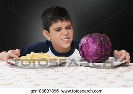 Boy choosing between a plate of French fries and a red cabbage View Large Photo Image Stock Photograph - Boy choosing between a plate of French fries and a red cabbage. Fotosearch