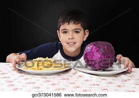 Boy choosing between a plate of French fries and a red cabbage View Large Photo Image Stock Photograph - Boy choosing between a plate of French fries and a red cabbage. Fotosearch