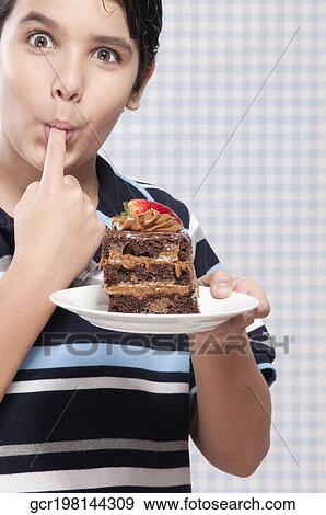Stock Photo - Boy eating a chocolate cake. Fotosearch