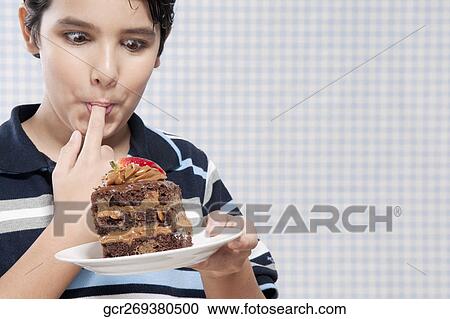 Boy eating a chocolate pastry View Large Photo Image Stock Image - Boy eating a chocolate pastry. Fotosearch