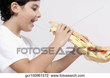Boy eating a submarine sandwich View Large Photo Image Stock Image - Boy eating a submarine sandwich. Fotosearch