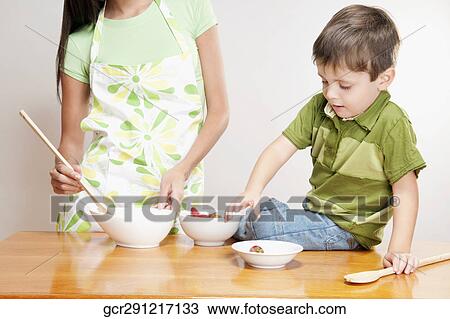 Stock Image - Boy helping his mother in cooking. Fotosearch