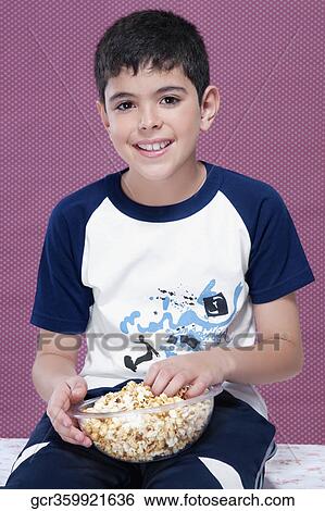 Boy holding a bowl of popcorn and smiling View Large Photo Image Stock Photograph - Boy holding a bowl of popcorn and smiling. Fotosearch