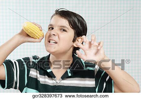 Boy holding a corn cob and looking angry View Large Photo Image Stock Image - Boy holding a corn cob and looking angry. Fotosearch