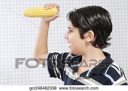 Boy holding a corn cob View Large Photo Image Stock Photo - Boy holding a corn cob. Fotosearch