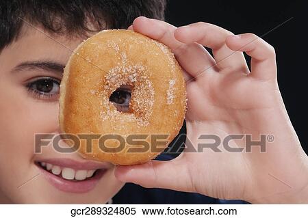 Boy holding a donut in front of his eye View Large Photo Image Stock Photography - Boy holding a donut in front of his eye. Fotosearch