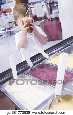 Boy holding a glass of chocolate milkshake in an ice cream parlor View Large Photo Image Stock Photo - Boy holding a glass of chocolate milkshake in an ice cream parlor. Fotosearch