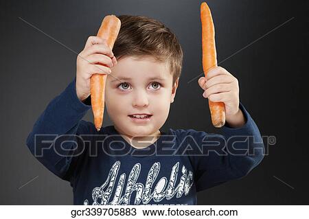 Stock Image - Boy holding two carrots. Fotosearch