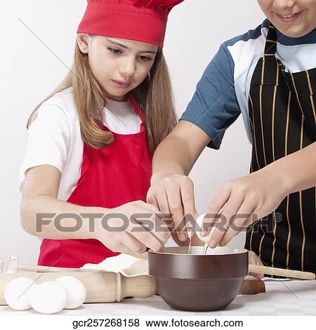 Stock Photo - Boy preparing a cake with his sister. Fotosearch