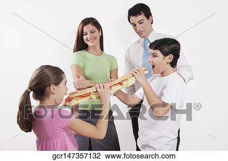 Stock Image - Boy sharing a submarine sandwich with his sister. Fotosearch