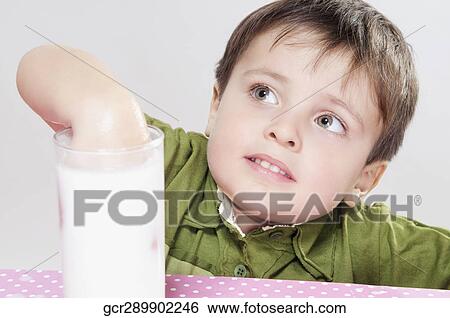 Stock Photograph - Boy soaking his hand in to a glass of milk. Fotosearch