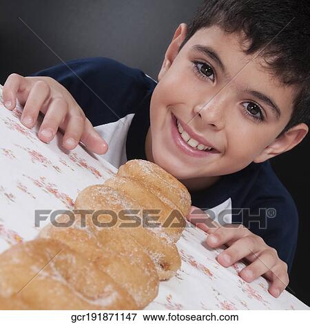 Boy with a line of donuts at a table View Large Photo Image Stock Photo - Boy with a line of donuts at a table. Fotosearch