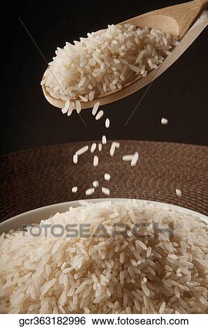 Brown rice being poured into a bowl from a wooden spoon View Large Photo Image Stock Photograph - Brown rice being poured into a bowl from a wooden spoon. Fotosearch