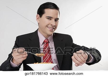 Stock Image - Businessman checking the time at breakfast table. Fotosearch