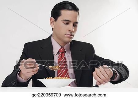 Stock Photo - Businessman checking the time at breakfast table. Fotosearch