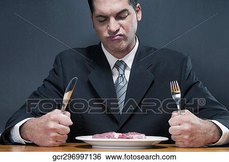 Businessman frowning at a raw steak View Large Photo Image Stock Photograph - Businessman frowning at a raw steak. Fotosearch