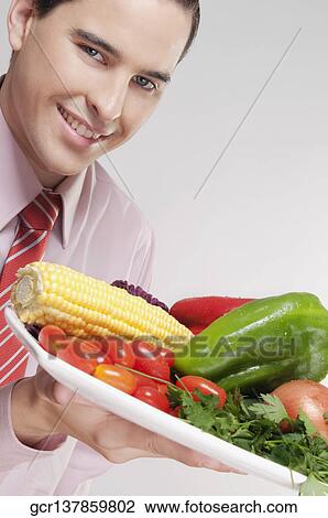 Businessman holding a platter of fresh vegetables View Large Photo Image Stock Image - Businessman holding a platter of fresh vegetables. Fotosearch