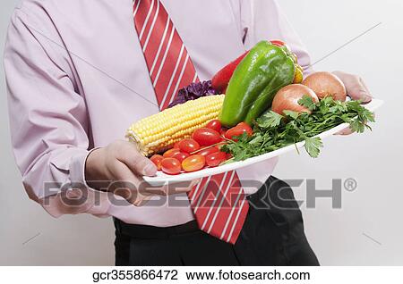 Businessman holding a platter of fresh vegetables View Large Photo Image Stock Image - Businessman holding a platter of fresh vegetables. Fotosearch