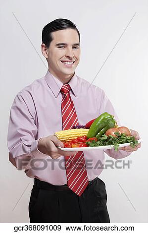 Businessman holding a platter of fresh vegetables View Large Photo Image Stock Photo - Businessman holding a platter of fresh vegetables. Fotosearch
