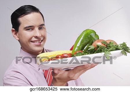 Businessman holding a platter of fresh vegetables View Large Photo Image Stock Photography - Businessman holding a platter of fresh vegetables. Fotosearch