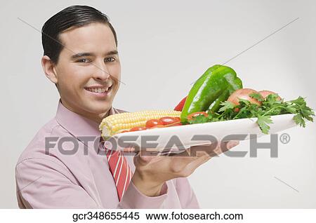Businessman holding a platter of fresh vegetables View Large Photo Image Stock Photography - Businessman holding a platter of fresh vegetables. Fotosearch