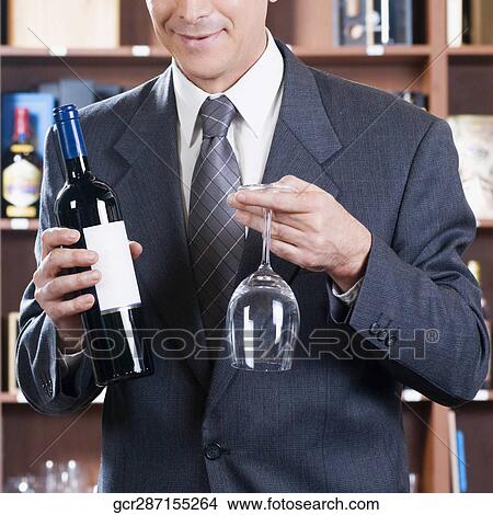Businessman holding a wine bottle and a wine glass View Large Photo Image Picture - Businessman holding a wine bottle and a wine glass. Fotosearch